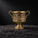 Antique brass urn on dark sand.webp